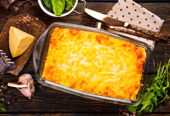 Rectangular glass bowl filled with mashed potato, underneath which is fish in cheese sauce. - 720308088