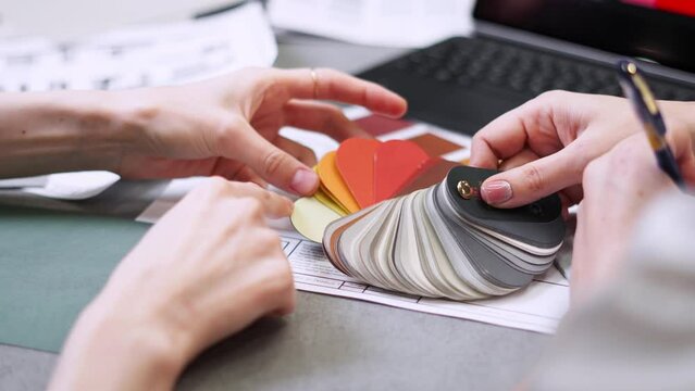 Close up hand choosing color from color sample swatch. The designer works with the customer and recommends the colors of decorative coatings.