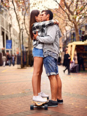 Couple, skateboarding and kissing in city, in love and excited to learn together and romantic...