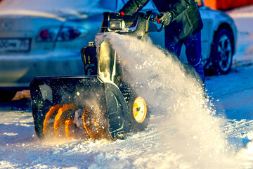 Close-up of a snow blower. Snow removal in winter. A worker sweeps snow in the courtyard of a house.