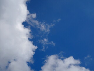 Obraz premium Dense white clouds are on the left of the image, with a bright blue sky on the right. The bright blue sky and fluffy white clouds are the beauty of nature. The atmosphere of the sky in the calm evenin