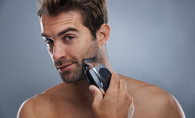 Man, beard and electric razor in studio portrait for grooming, skincare and wellness by grey...