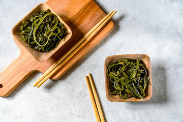 Artisanal Kelp Noodle or seaweed salad in Bowls on Wooden Serving Board, top view, light background