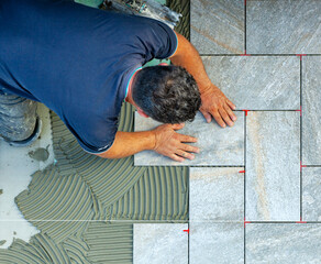 Tiler carefully lays every single tile with the help of a wire to respect the geometry of the...