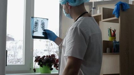 A doctor diagnoses the disease lung cancer in a hospital office, a radiologist examines an x-ray of a person's lungs in a hospital. The doctor diagnoses pneumonia. Pulmonary turbeculosis