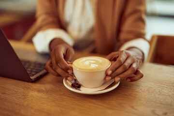 A close-up of a female hands holding a cup of cappuccino, latte art.
