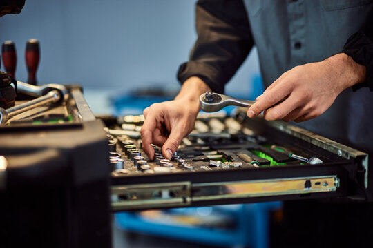 A mechanic man looking for some tools in his drawer, working at the repair shop.
