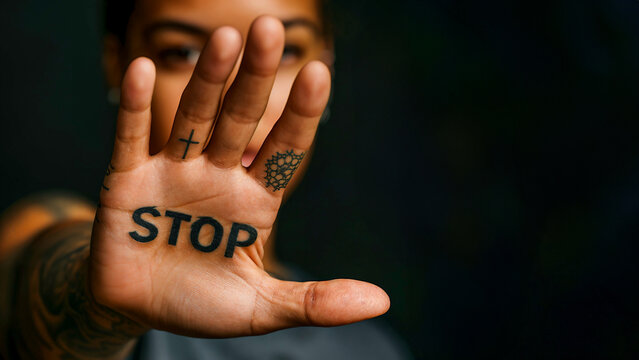 Hand with 'STOP' tattoo and symbols, gesture for ending violence.