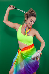 Young woman in colorful carnival clothing playing a tambourine, isolated on a green background