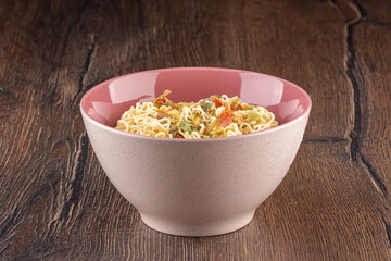 Dry instant noodles with dry vegetables and spices in a bowl.