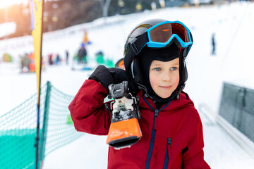 Cute adorable little kid boy enjoy having fun walking with ski on shoulder at alpine mountain...