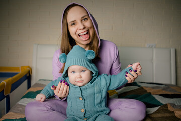 A young mother and her little daughter are playing and frolicking on the bed