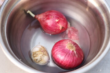 Indian Onion and garlic in a steel bowl under bright light, steel