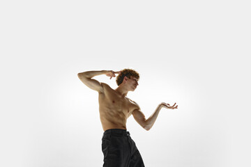 Elegance solo. Athletic man in black pants posing against white studio background. Contemporary...