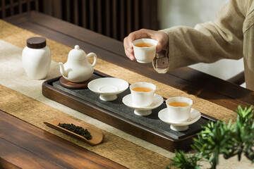 Image of tea set, person making Asian-style tea, tea cup and teapot - obrazy, fototapety, plakaty