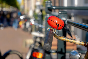 Selective focus of red bell on handlebar of bicycle in Amsterdam, Outdoor parking area with blurred...