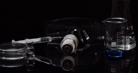 Laboratory Equipement: Syringe and Medicine, Test Tubes and Flasks Rotating on Black Background.