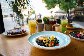 Black tagliatelle pasta with shrimp, chili and garlic on an outdoor table