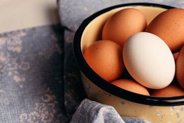 a white egg surrounded by brown eggs in a bowl. Food concept.