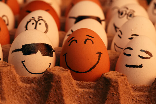 Fotograf&iacute;a de huevos blancos y marrones con caras graciosas. 