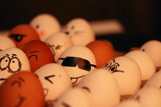 Fotografía de huevos blancos y marrones con caras graciosas. 
