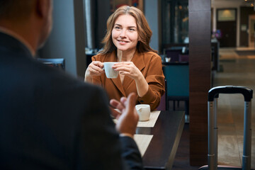 Cheerful lady sitting at the table with coffee cup in hands