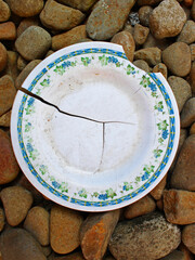 Top view of a broken plastic plate on the gravel. 