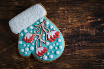 Whimsical mitten shaped Christmas cookies, rowan tree icing, snowy accents, on a rustic wooden backdrop.