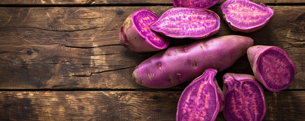Obraz na płótnie Canvas Purple sweet potatoes on a wooden background, top view. Sweet potatoes for background.