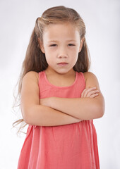 Angry, girl and child in studio with arms crossed, frustrated in portrait and emotion, cross or upset on white background. Facial expression, rage and conflict with tantrum, furious and bad attitude