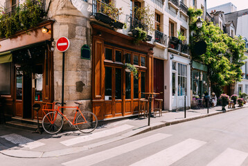 Cozy street with with tables of cafe and old bicycle in Paris, France. Architecture and landmarks of Paris. Postcard of Paris