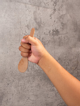hand holding wooden tablespoon on gray background