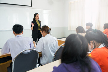 Asian female university explaining lesson to the students in the classroom