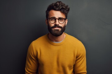 Obraz premium A man with a beard wearing glasses and a sweater poses for the camera, Young handsome man with beard wearing casual sweater and glasses, AI Generated