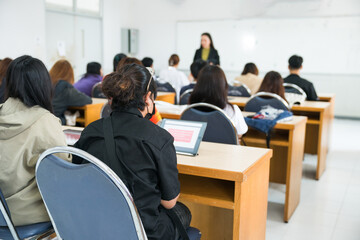 Fototapeta premium Rearview of university students listen to lecturer explaining lesson in the classroom