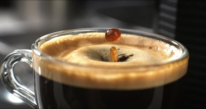 Super slow motion macro of hot creamy aromatic close up coffee  drop is splashing in transparent mug before being served to customer at cafe or bar at 1000 fps.