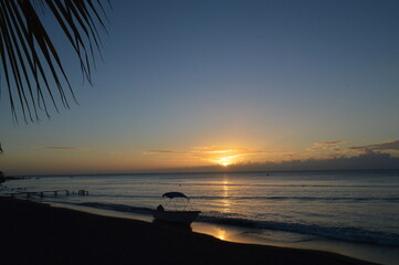 Sunset at the beach silhouette of boat and palm branches. Palmar de Ocoa. Dominican Republic