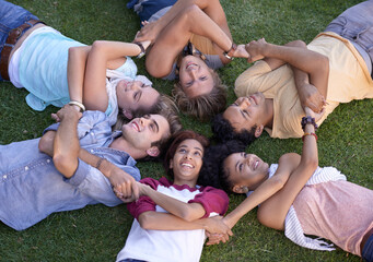 Fototapeta premium Relax, friends and group holding hands on grass at park on vacation, holiday or summer. Top view, smile and team of students on lawn, circle in nature and community of young people together outdoor