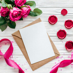 Card near pink decorations, seals and silk ribbons on white table top view, wedding mockup