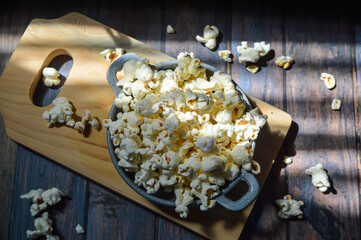 Popcorn in a small pan on a wooden background, selective focus.