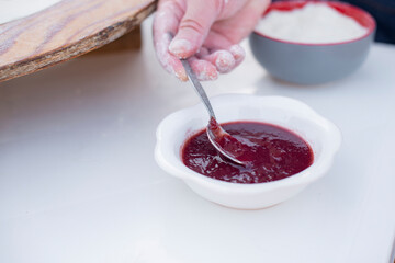 Close up of old female cook, chef making pita, taking sauce, ketchup with spoon, cooking outdoor. Concept of street food.