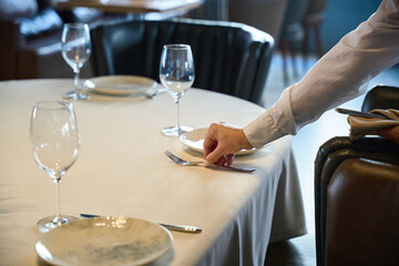 Waitress in a cozy restaurant lays out cutlery