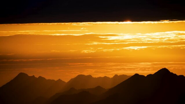 Silhouettes of mountains in golden sunset. Moving clouds in orange sky. Warm winter mountain scenery in northern Taiwan, Shuangxi Buyanting Pavilion.