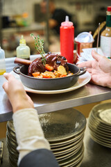 Restaurant staff serves meat garnished with a sprig of thyme