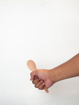 hand holding wooden tablespoon on gray background