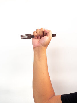 hand holding wooden tablespoon on gray background