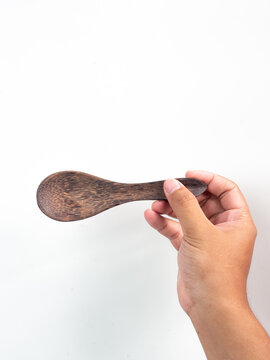 hand holding wooden tablespoon on gray background