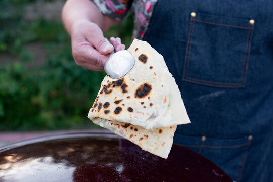 Close up of female chef, coock holding pita, taco, shawurma. frying, baking on frying pan outdoor. Consept of fast food.