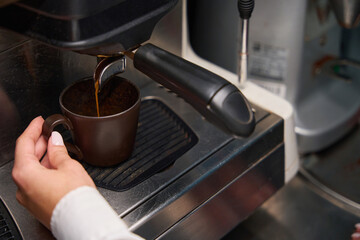 Female barista prepares coffee in a coffee machine