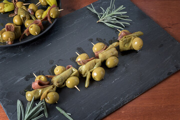 Gildas, typical Euskadi tapa, presented on a slate stone with sprigs of rosemary